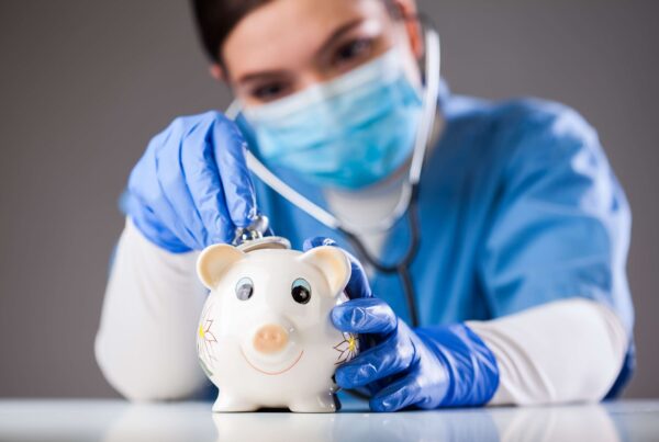 Doctor inspecting piggy bank with stethoscope