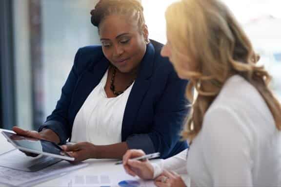 Black businesswoman showing white client something on an ipad.