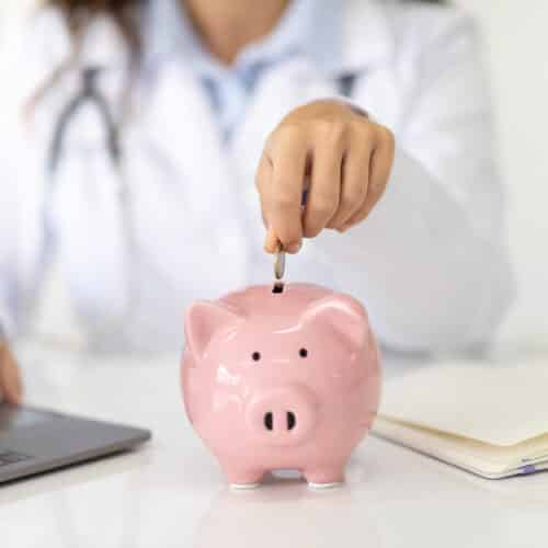 physician adding money into a piggy bank (represents HSA)