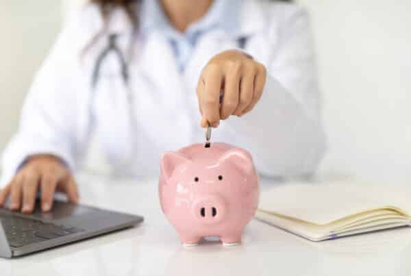 physician adding money into a piggy bank (represents HSA)