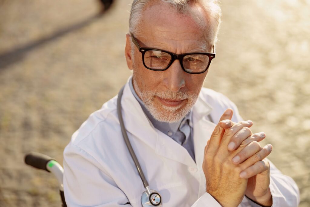 close up portrait of senior doctor in white coat and glasses sitting in a wheelchair