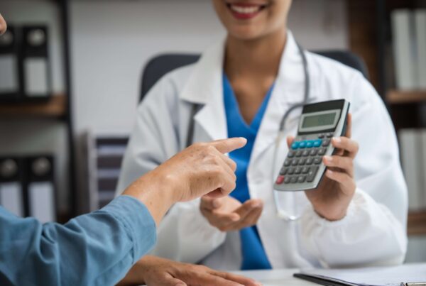 Young Chinese woman doctor in white coat with holding up a calculator and smiling