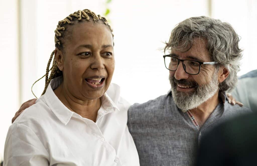 Man and woman smiling with their arms around each other's shoulders