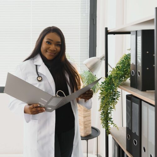 Black woman doctor in white coat checking charts