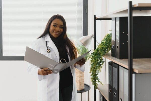 Black woman doctor in white coat checking charts